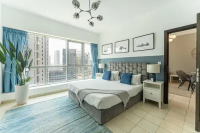 a bedroom with a large bed with blue walls and windows at HAVN -1 Bedroom Unit in Dubai Marina, Marina View in Dubai