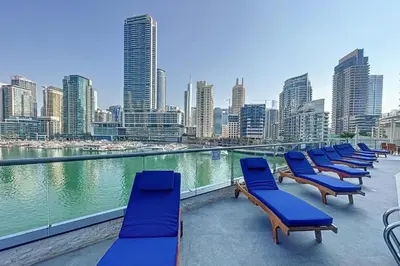 a row of blue chairs on a balcony with a city skyline at HAVN -1 Bedroom Unit in Dubai Marina, Marina View in Dubai