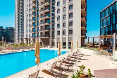 a swimming pool with chairs and umbrellas in front of a building at Park Heights Deluxe 1bedroom in Dubai