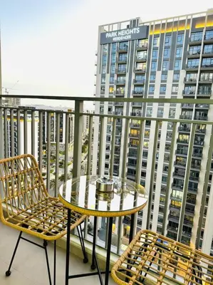 a table and chairs on a balcony with a large building at Park Heights Deluxe 1bedroom in Dubai
