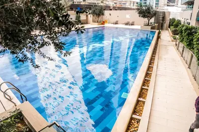 a swimming pool with blue water in a building at Perfect Studio Apartment Near to Metro Station in Dubai