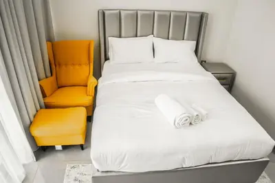 a bedroom with a bed and an orange chair at Perfect Studio Apartment Near to Metro Station in Dubai
