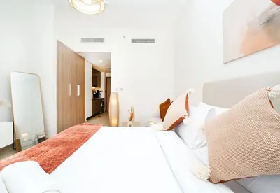 a white bedroom with a large white bed with pillows at EasyGo - Azizi Riviera 15 Community View in Dubai
