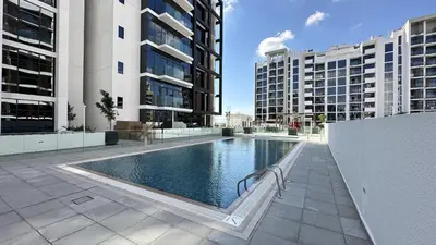 a swimming pool in the middle of two tall buildings at EasyGo - Azizi Riviera 15 Community View in Dubai