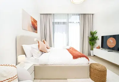 a white bedroom with a bed and a tv at EasyGo - Azizi Riviera 15 Community View in Dubai