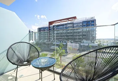 a balcony with two chairs and a table and a building at EasyGo - Azizi Riviera 15 Community View in Dubai