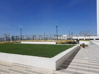 a park with a bench and grass in front of a building at Cosy 1 Bedroom in Damac Hills | OFEX in Dubai