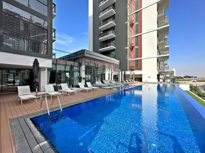 a large swimming pool with white chairs and a building at StoneTree - Brand new Studio in Mohammed Bin Rashid City in Dubai