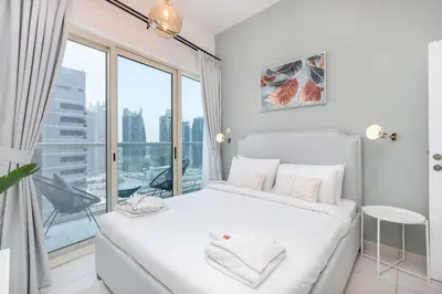 a bedroom with a white bed and a large window at HAVN - 2 Bedroom in Dubai Marina, 10min to Metro in Dubai
