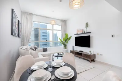 a living room with a table and chairs and a tv at HAVN - 2 Bedroom in Dubai Marina, 10min to Metro in Dubai