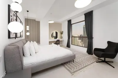 a bedroom with a bed and a chair and a window at Beautiful 2 Bedroom Retreat in the Heart of JBR in Dubai