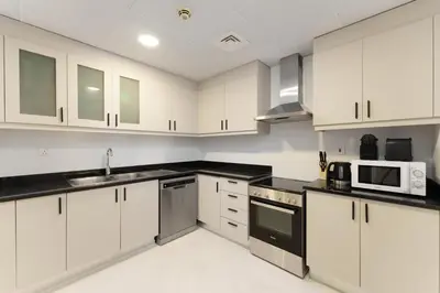 a kitchen with white cabinets and black counter tops at Beautiful 2 Bedroom Retreat in the Heart of JBR in Dubai