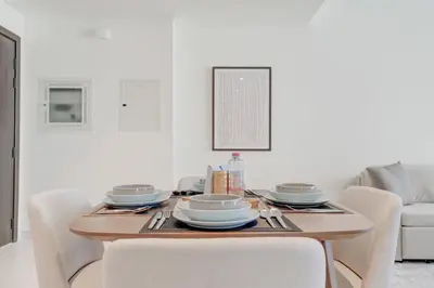 a dining room table with white chairs and a wooden table at Silkhaus Exquisite Sea View 1BDR At Marina Vista in Dubai