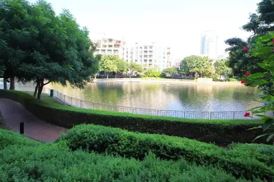 a park with a lake with trees and buildings at New Arabian The Links Canal 1 BR The Greens in Dubai