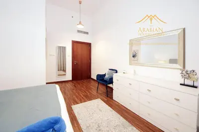 a bedroom with a bed and a dresser and a mirror at New Arabian The Links Canal 1 BR The Greens in Dubai