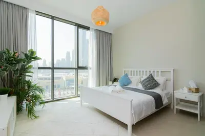 a white bedroom with a bed and a large window at Elite Escape Holiday Home - 2 BHK Getaway with Burj Khalifa View and Dubai Mall Access - 1507 in Dubai