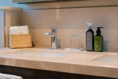 a bathroom counter with a sink and two bottles of alcohol at Elite Escape Holiday Home - 2 BHK Getaway with Burj Khalifa View and Dubai Mall Access - 1507 in Dubai