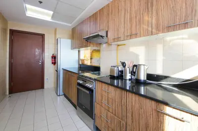a kitchen with wooden cabinets and a black counter top at RH- High-Floor Splendor, 2-Bedroom Gem in Downtown in Dubai