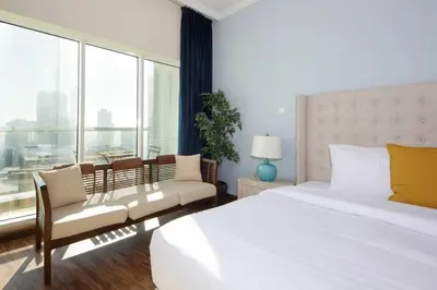 a bedroom with a bed and a couch and a window at RH- High-Floor Splendor, 2-Bedroom Gem in Downtown in Dubai