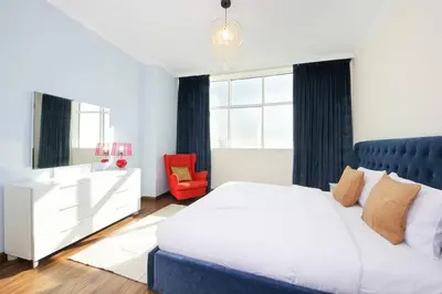 a bedroom with a white bed and a red chair at RH- High-Floor Splendor, 2-Bedroom Gem in Downtown in Dubai