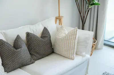 four pillows on a white couch in a living room at Elite Escape Holiday Home - 2 BHK Getaway with Dubai Mall Access - 1508 in Dubai