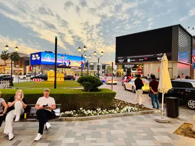 people sitting on a bench in front of a shopping mall at 1 BR Flat, Luxury amenities, Near JBR Beach & Club with FREE Parking in JBR in Dubai