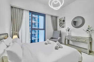 a bedroom with a white bed with a chair and a window at MAJESTIC Act Two 2BR- 27th Floor Burj Khalifa- Downtown Dubai in Dubai