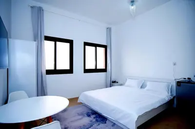 a white bedroom with a bed and a table at Your Silicon Oasis Comfort Haven in Dubai