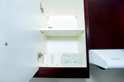 a bathroom with a shelf with glasses and towels at Your Silicon Oasis Comfort Haven in Dubai