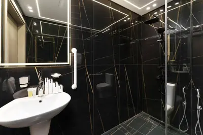 a black tiled bathroom with a sink and a shower at Luxury Living in 1 bedroom apartment in JVC in Dubai
