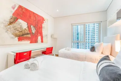 two beds in a room with two red chairs at 2 BR Marina View in Marina Heights By PK Holidays in Dubai