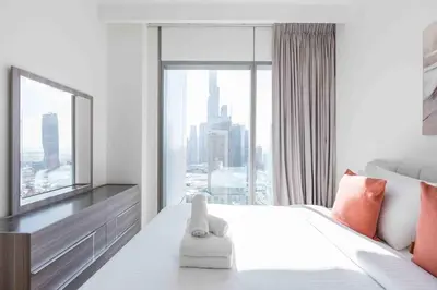 a bedroom with a large white bed with a large window at Downtown Views II Burj Khalifa View, Downtown Dubai - Mint Stay in Dubai