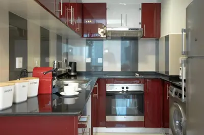 a kitchen with red cabinets and a stove at Cozy Spacious Apartment 1BR in Dubai