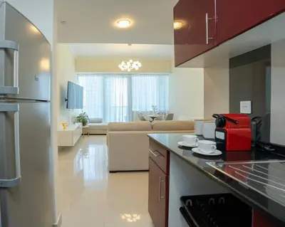 a kitchen with a counter top and a living room at Cozy Spacious Apartment 1BR in Dubai