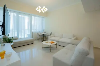 a white living room with a couch and a table at Cozy Spacious Apartment 1BR in Dubai