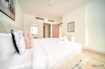 a bedroom with a white bed and a white couch at Special Offer Stylish 1BR with Scenic Views & Pool by Deluxe Holiday Homes in Dubai