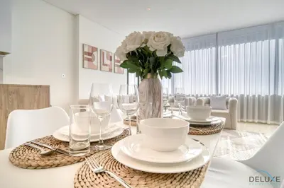 a dining room table with a vase of flowers and glasses at Special Offer Stylish 1BR with Scenic Views & Pool by Deluxe Holiday Homes in Dubai