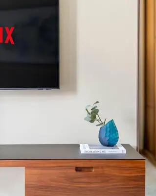 a vase sitting on a book next to a tv at GuestReady - Contemporary delight in Dubai in Dubai