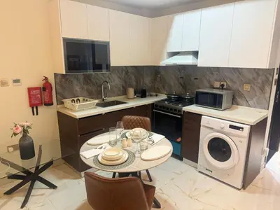 a kitchen with a table and a washing machine at Jwelz By Danube in Dubai