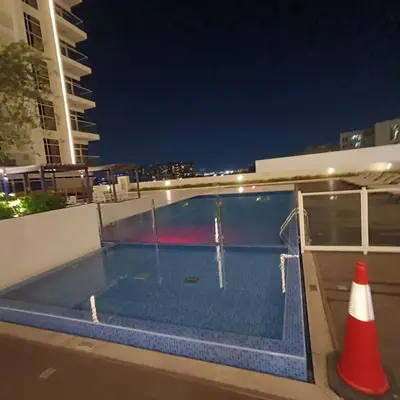 an empty swimming pool at night with a traffic cone at Jwelz By Danube in Dubai
