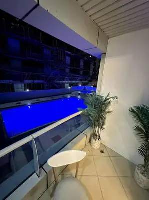 a balcony with a swimming pool with a table and a stool at Dubai Marina - Huge Luxury Studio Apartment in Dubai