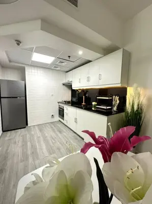a kitchen with white cabinets and pink flowers in a room at Dubai Marina - Huge Luxury Studio Apartment in Dubai