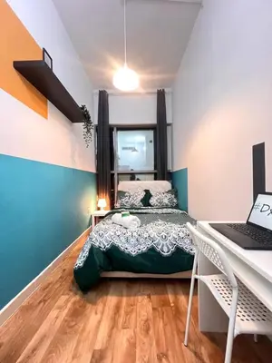 a bedroom with a bed and a desk with a laptop at Relaxing Closed Partition Room in Tecom Near Metro in Dubai