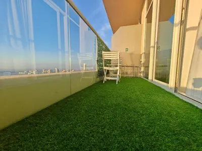 a chair on the balcony of a building with green grass at LeModCasa: Smart, modern studio in JVC in Dubai