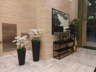 two black vases with white flowers in a lobby at LeModCasa: Smart, modern studio in JVC in Dubai