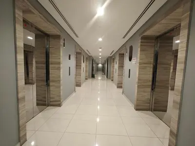 a long hallway with wooden doors and a white tile floor at LeModCasa: Smart, modern studio in JVC in Dubai