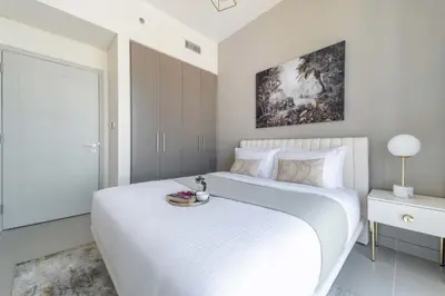 a white bedroom with a large bed and a painting at Frank Porter - Forte Tower 1 in Dubai