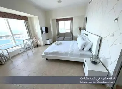 a bedroom with a large white bed and a chair at Ensuite Rooms in CoLiving Apartments in Marina in Dubai