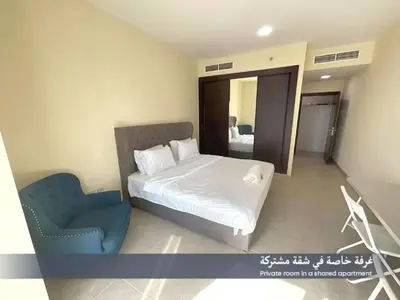 a bedroom with a bed and a blue chair at Ensuite Rooms in CoLiving Apartments in Marina in Dubai