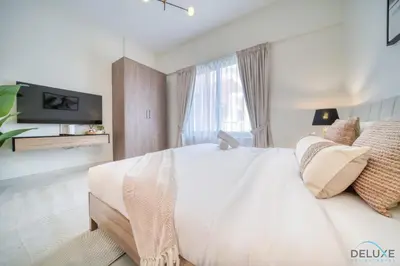 a bedroom with a large white bed and a tv at Stylish Studio Apartment at Casa Grande, JVC by Deluxe Holiday Homes in Dubai